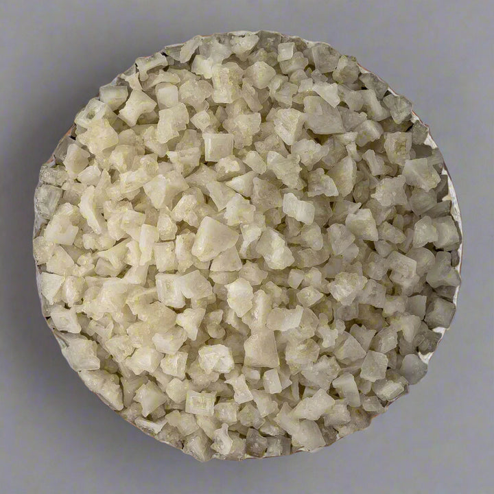 Close-up of a round container filled with small, light-colored stones on a wooden surface.