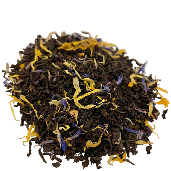 Dry black tea leaves with yellow and purple flowers on a white background