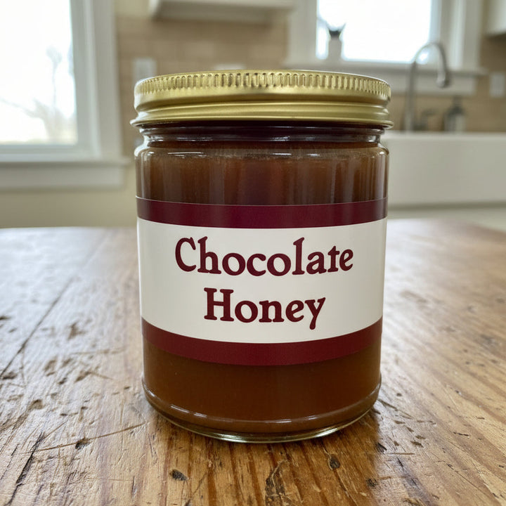Jar of chocolate honey with a gold lid on a white surface